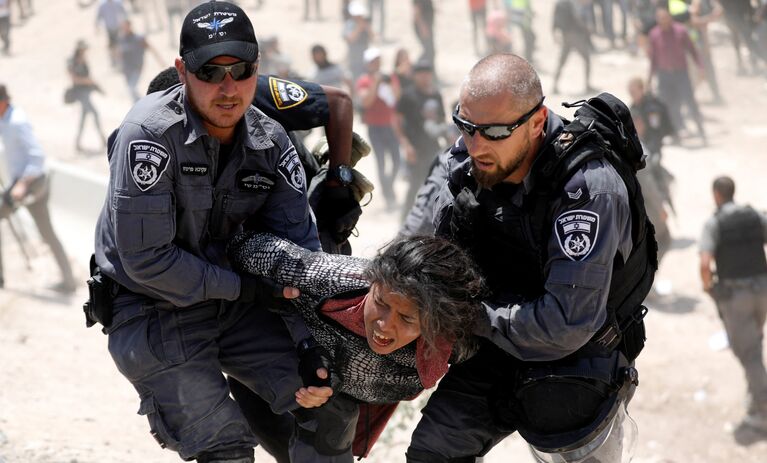 Израильские полицейские задерживают палестинскую девушку в деревне бедуинов Хан аль-Ахмара возле Иерихона на Западном берегу Иордан. 4 июля 2018 года
