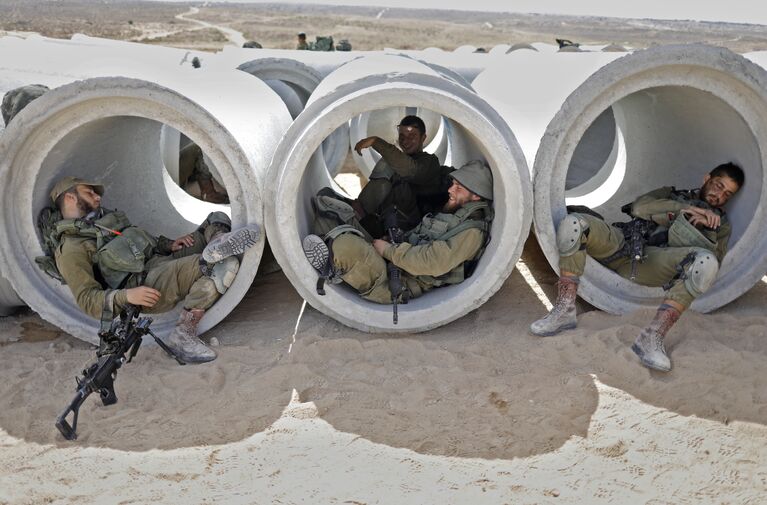 Израильские военнослужащие из пехотной бригады Кфир отдыхают в бетонных трубах во время военных учений на военной базе Цеелим, Израиль