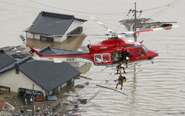 Cпасатели эвакуируют местного жителя из затопленного дома на юге Японии. 7 июля 2018