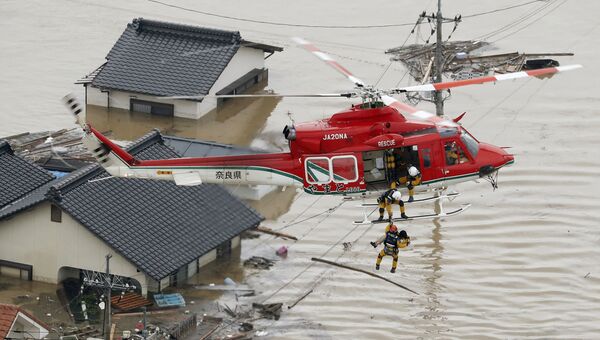 Cпасатели эвакуируют местного жителя из затопленного дома на юге Японии. 7 июля 2018