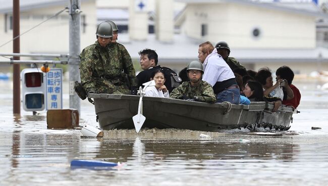 Cпасатели эвакуируют местных жителей из затопленного района на юге Японии. 7 июля 2018