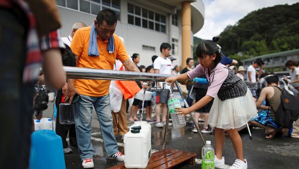 Местные жители получают питьевую воду в городе Михара, префектура Хиросима, Япония. 9 июля 2018 года