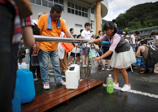 Местные жители получают питьевую воду в городе Михара, префектура Хиросима, Япония. 9 июля 2018 года
