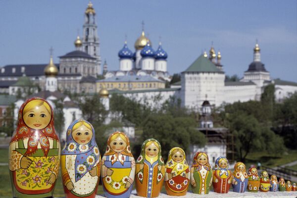 Русские матрешки, сфотографированные на фоне Троице-Сергиевой лавры