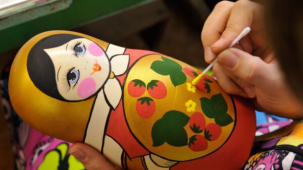 Сотрудница производственного художественного объединения Хохломская роспись расписывает матрешку в цехе предприятия