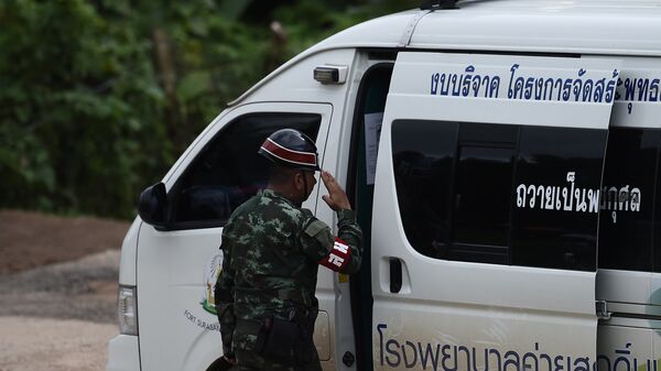 Тайская военная полиция приветствует машину скорой помощи, покидающую пещерную зону пещер Тхам Луанг. 10 июля 2018