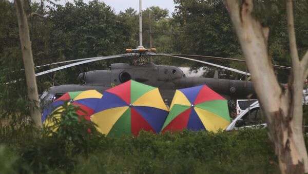Полиция Таиланда размещает зонты вокруг эвакуационного вертолета, где находятся мальчики и их тренер, извлеченный из пещеры в провинции Чианг Рай, на севере Таиланда. 10 июля 2018