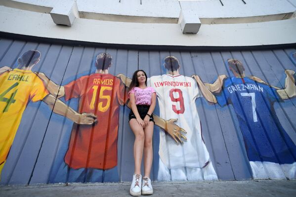 Девушка на фоне граффити с изображение игроков всех сборных чемпионата мира по футболу 2018