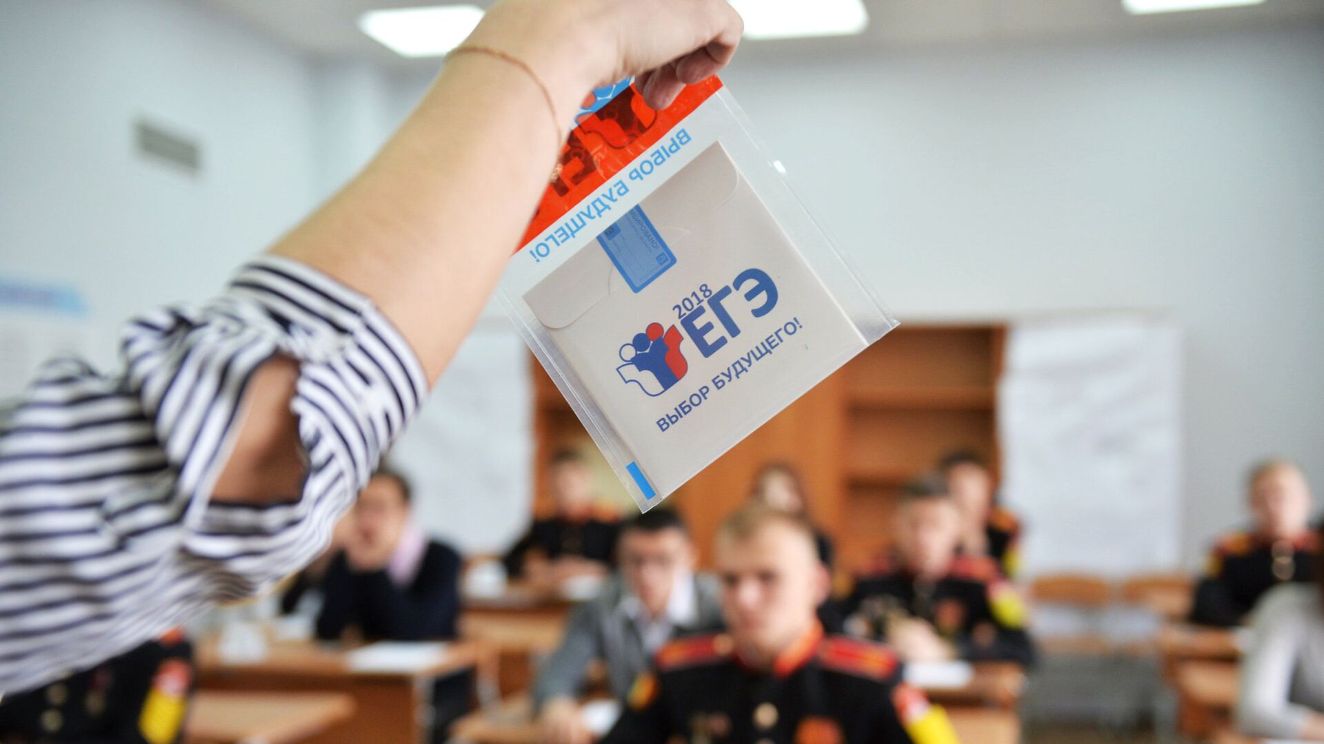 Преподаватель демонстрирует пакет и компакт-диск с заданиями перед началом ЕГЭ по математике - РИА Новости, 1920, 29.02.2024