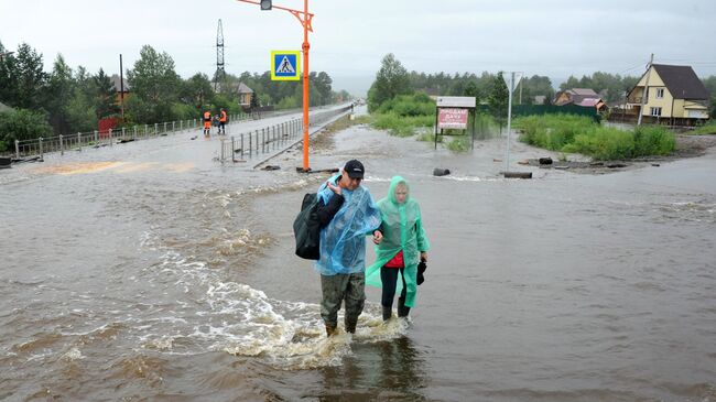 Местные жители на затопленной в результате паводка улице в Чите