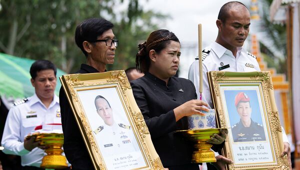 Почетный караул с фотографией 38-летнего Самана Кумана, бывшего члена элитного военно-морского подразделения флота Таиланда SEAL, который погиб при спасении детской футбольной команды из затопленной пещеры. 6 июля 2018