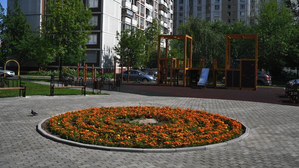 Детская игровая площадка и цветочная клумба во дворе дома в Москве. Архивное фото