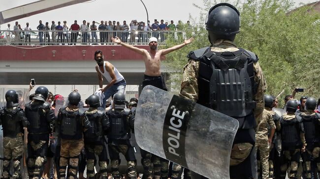 Иракская полиция и демонстранты возле здания администрации провинции Басра на юге Ирака. Архивное фото