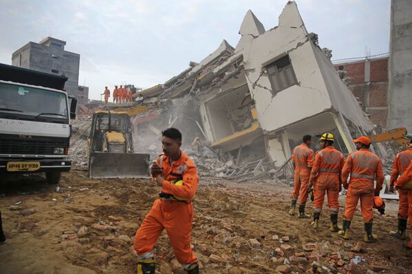 Спасатели работают на месте обрушения здания в деревне Шахебери к востоку от Нью-Дели, Индия