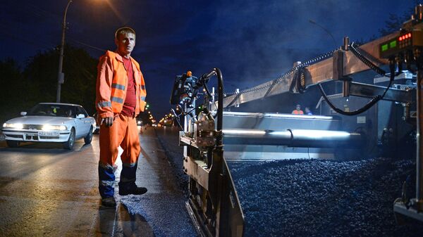 Рабочий во время укладки асфальта по приоритетному проекту Безопасные и качественные дороги на улице Немировича-Данченко  в Новосибирске. 20 июля 2018