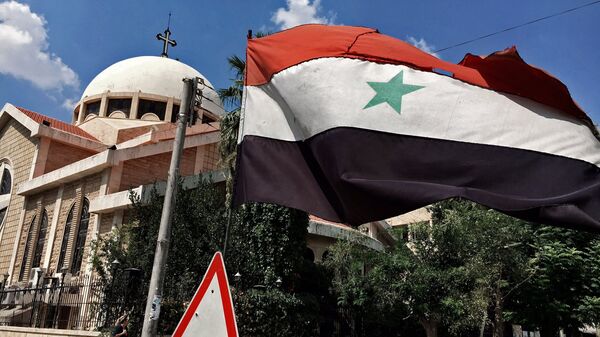 Государственный флаг Сирийской Арабской Республики у православной церкви в старом христианском квартале города Алеппо