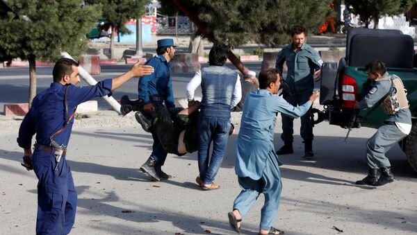 Афганские полицейские несут раненых с места взрыва в Кабуле, Афганистан. 22 июля 2018