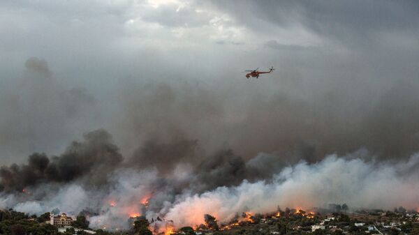 Пожарный вертолет пролетает над лесным пожаром