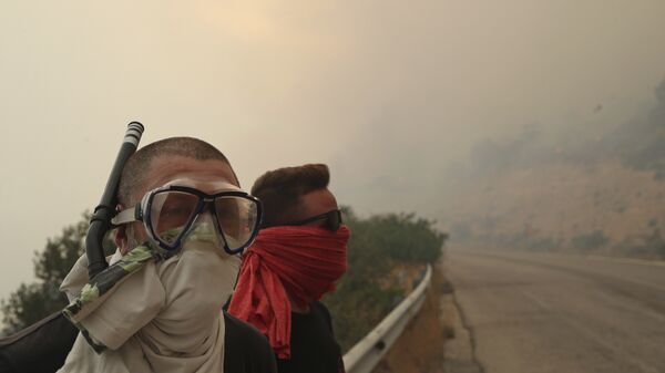 Люди закрывают лица от дыма во время лесного пожара