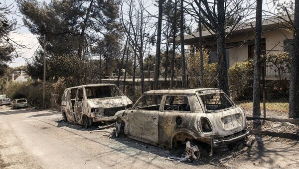 Сгоревшие в результате лесных пожаров автомобили на улице Мати в Греции. 25 июля 2018
