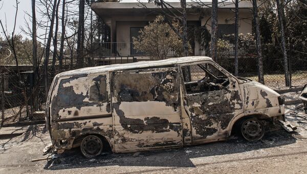 Сгоревший в результате лесных пожаров автомобиль на улице Мати в Греции. Архивное фото