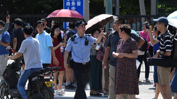 Офицер полиции Китая среди толпы людей собравшихся возеле посольства США в Пекине, где произошел взрыв. 26 июля 2018