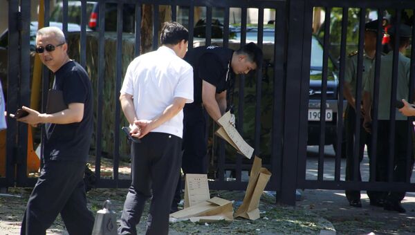 Сотрудник службы безопасности собирает предметы с места происшествия возле посольства США в Пекине, Китай. 26 июля 2018