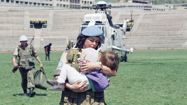 Женщина-солдат ООН несет двухлетнюю девочку, которую эвакуировали из города Горажде в Сараево, 25 апреля 1994 года