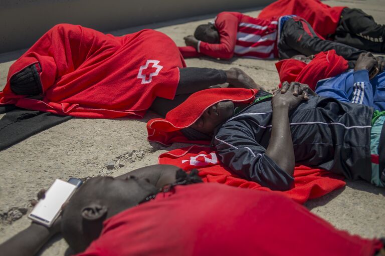 Мигранты, закутанные в одеяла Красного Креста, после прибытия на борт береговой охраны в гавани Тарифы. 14 июля 2018