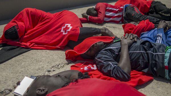 Мигранты, закутанные в одеяла Красного Креста, после прибытия на борт береговой охраны в гавани Тарифы, Испания. 14 июля 2018