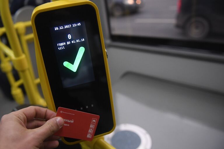 Пассажир прикладывает билет к валидатору в автобусе в Москве