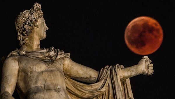 Луна во время затмения рядом со статуей древнегреческого Бога Аполлона в центре Афин, Греция. 27 июля 2018