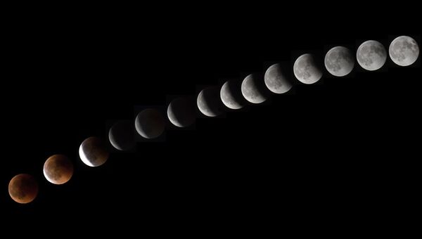 Комбинация из 14 фотографий показывает Луну во время полного лунного затмения недалеко от города Ла-Пуэнте на острова Тенерифе. 27 июля 2018