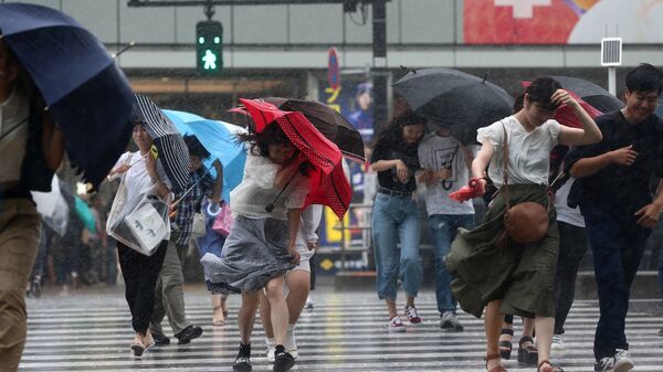 Жители Токио с зонтами спасаются от обрушившегося на город  тайфуна Джондари. 28 июля 2018