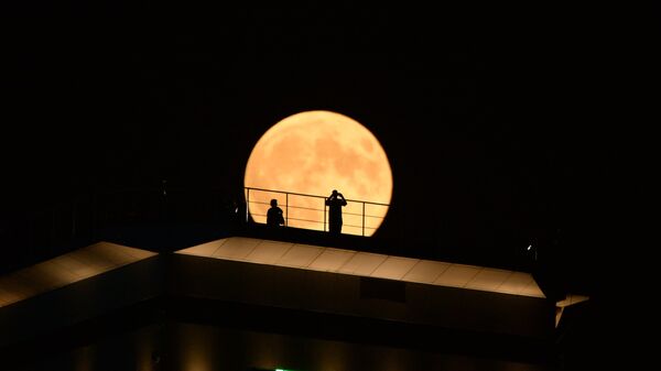 Луна во время затмения на фоне здания высотного комплекса Грозный сити в Грозном
