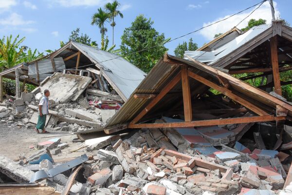 Местный житель осматривает разрушенный землетрясением дом на острове Ломбок в Индонезии.
