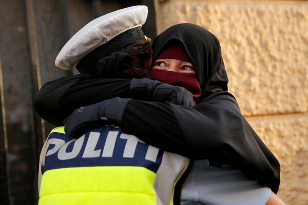 Женщина обнимает полицейского во время демонстрации против запрета на ношение паранджи в Дании. 1 августа 2018 года.