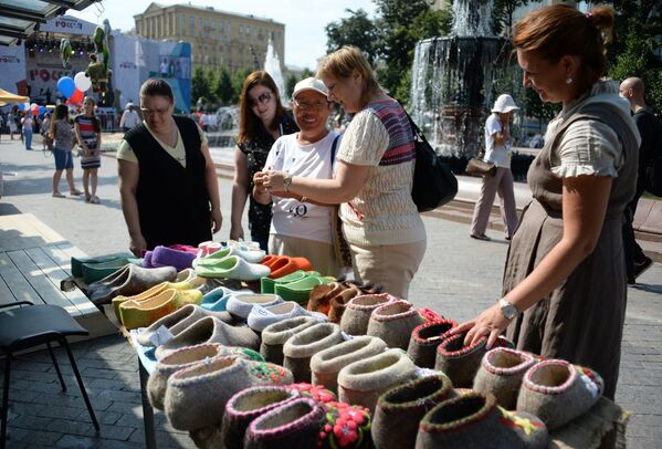 Посетители у прилавка с валяной обувью на фестивале Многонациональная Россия в Москве