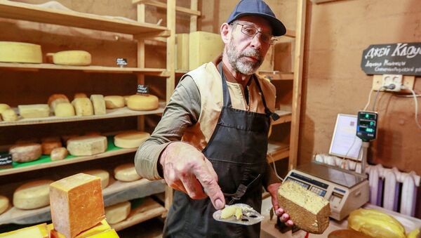 Фермер Джей Роберт Клоуз нарезает сыр в магазине при ферме в Московской области, деревни Мошницы