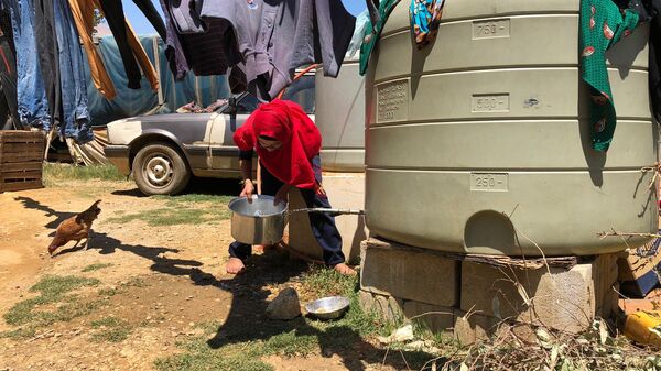 Женщина набирает воду в палаточном лагере для сирийских беженцев. Архивное фото
