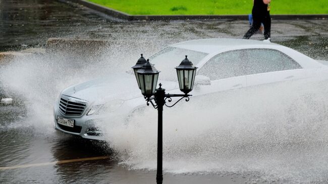 Автомобиль едет по улице Москвы во время дождя