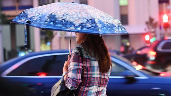 Женщина переходит дорогу во время дождя в Москве