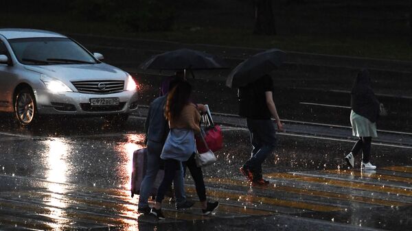 Прохожие переходят дорогу во время дождя в Москве. Архивное фото