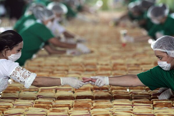 Женщины готовят сотни хот-догов, чтобы побить рекорд Гиннеса самой длинной линии из хот-догов в Гвадалахаре, штат Халиско. 12 августа 2018 года