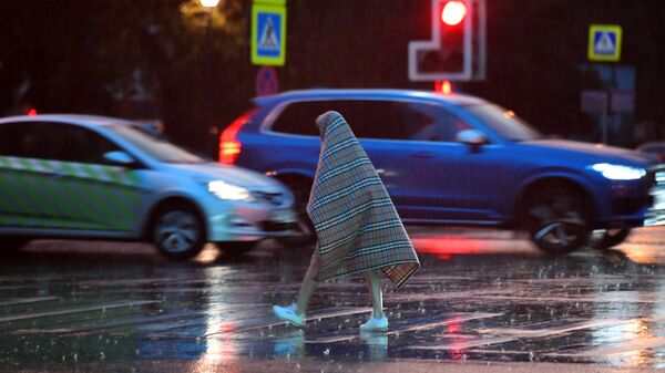 Прохожий переходит дорогу во время дождя в Москве. Архивное фото
