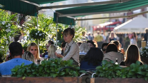 Посетители в летнем кафе в Климентовском переулке в Москве