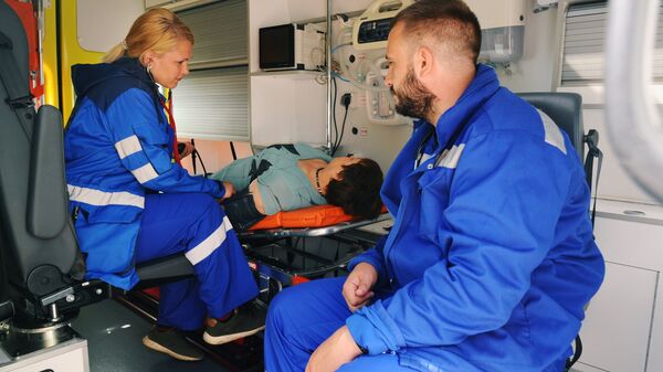Врач скорой медицинской помощи оказывают первую помощь пациенту в салоне реанимобиля