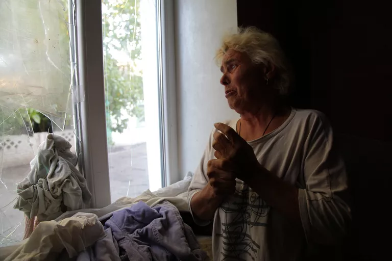 Жительница поселка Веселое показывает свой дом, попавший под обстрел Жительница поселка Веселое показывает свой дом, попавший под обстрел