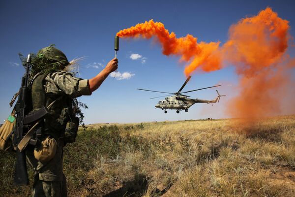 Военнослужащий во время ротно-тактических учений Южного военного округа на полигоне Прудбой в Волгоградской области. На втором плане - вертолет Ми-8