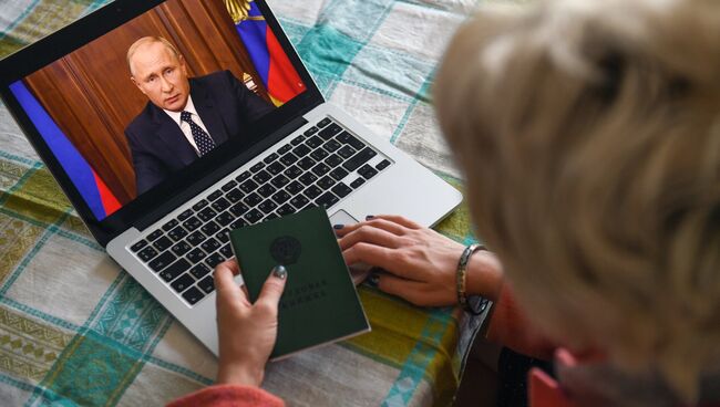 Жительница Новосибирска смотрит трансляцию обращения президента РФ Владимира Путина к гражданам России